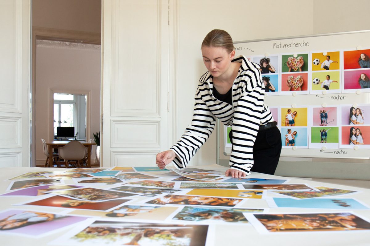 Twentyone Brands Einblick in die Agentur, eine Mitarbeiterin vor einem betrachtet Bilder eines Projekts.